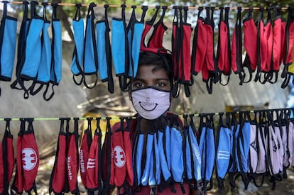 Un vendedor ambulante posa junto a su puesto de mascarillas en una calle de Hyderabad (India).