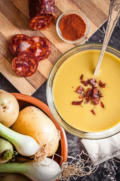 <p> <b> Ingredientes</b></p><p> Para 6 personas: 1 patata (o 2) de unos 300 gramos, la parte blanca de un puerro, 2 nabos, 1 cebolla de unos 300 gramos (o 2 cebolletas), 3 zanahorias, ½ kilo de calabaza, 750 mililitros de caldo de verduras o pollo, 200 mililitros de leche evaporada, aceite de oliva virgen extra, 1 cucharadita de pimentón de La Vera, 100 gramos de chorizo ibérico en un trozo. </p><p> <b> Preparación</b></p><p> 1. Pelar y cortar toscamente las verduras. Saltearlas en una olla profunda con un fondo de aceite de oliva y un poco de sal hasta que se doren. 2. Cubrir con el caldo y hervir a fuego medio durante unos 10 minutos o hasta que las verduras estén tiernas. 3. Triturar añadiendo el pimentón de La Vera y la leche evaporada. 4. Cortar el chorizo en dados pequeños. En una sartén a fuego bajo, cocinarlo hasta que pierda la grasa y tenga una textura crujiente. 5. Servir la crema bien caliente con un poco del crujiente de chorizo ibérico encima. </p>