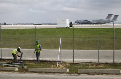 Dos obreros trabajan junto a las pistas del aeropuerto. Al fondo dos Galaxy de la U.S. Air Force.