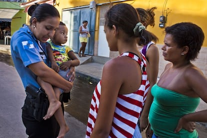 Lidia, policial militar, pergunta as vizinhas se conhecem a criança que leva no colo. Um vizinho a levou na UPP de Nova Brasília, no Complexo de Alemão, depois de encontrá-la perdida.