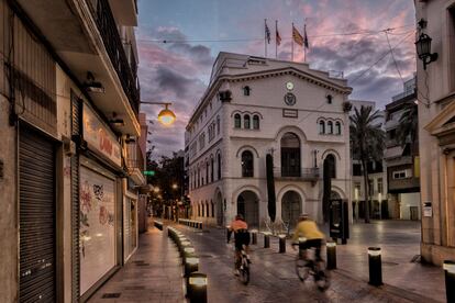 Dos ciclistas pedalean por delante del edificio histórico del Ayuntamiento en la plaza de la Vil.la, en Badalona. / CARLES RIBAS