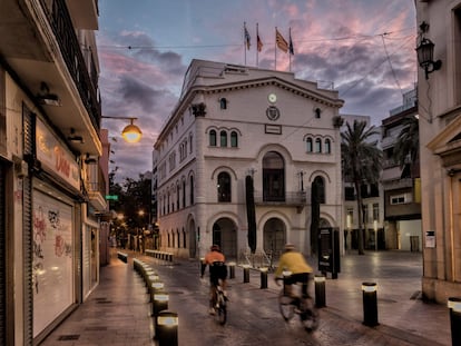 Dos ciclistas pedalean por delante del edificio histórico del Ayuntamiento en la plaza de la Vil.la, en Badalona. / CARLES RIBAS