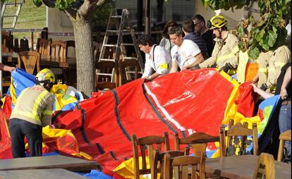 Operarios y bomberos retiran el castillo hinchable.