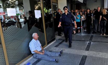 Giorgos Chatzifotiadis llora sentado en el suelo a las puertas de un banco en Tesal&oacute;nica.