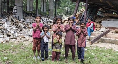Niños y niñas frente a un colegio en ruinas en Nepal