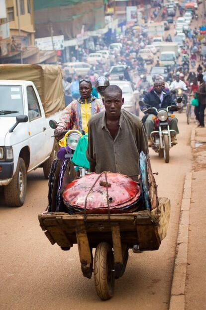Un trabajador transporta un tambor de acero en una carretilla en Kampala (Uganda).