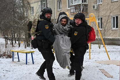 Ukraininan Police officers carry a local resident injured as a result of a missile attack in Kharkiv on January 23, 2024. 
