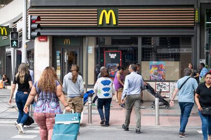 Un grupo de peatones cruzan la calle delante de un restaurante McDonald's en la zona Cuatro Caminos en Madrid.