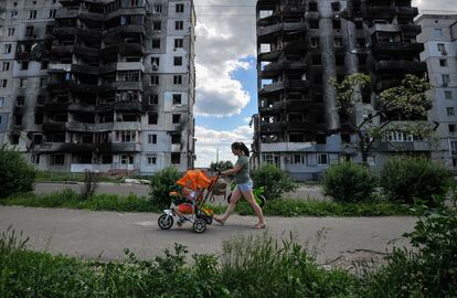 Ucrania. Una mujer pasea con un niño delante de edificios destruídos por los bombardeos rusos en la ciudad de Borodyanka en junio de 2022. 