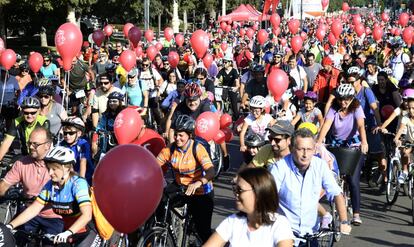 Un gran número de ciclistas han atado un globo rojo a su bici. 