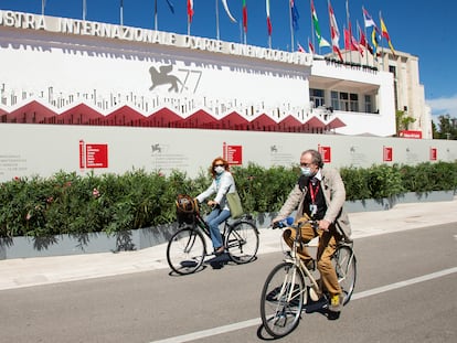 Asistentes al festival pasean en bicicleta frente al palacio del festival, este martes en Venecia.