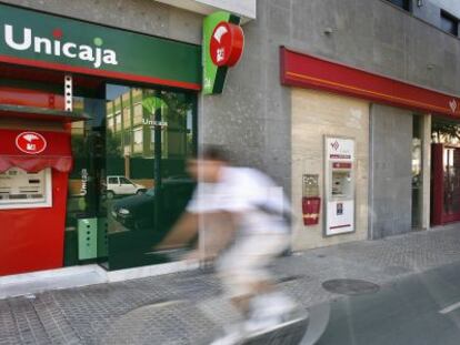 Un ciclista cruza frente a oficinas de Unicaja y Cajasur, en Sevilla.