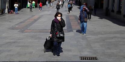 A woman wears a protective mask as she walks in the unusually quiet Preciados street in central Madrid, Spain, March 13, 2020. REUTERS/Sergio Perez