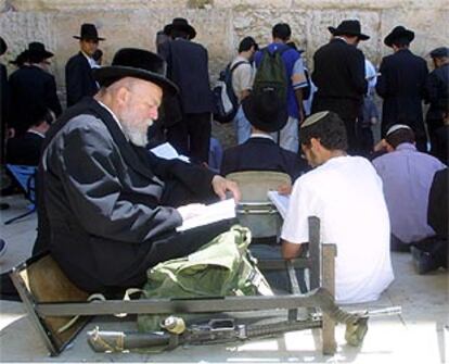 Un hombre lee un libro sagrado ante el Muro de las Lamentaciones, ayer durante la conmemoración de la destrucción del primer y segundo templo de Jerusalén.