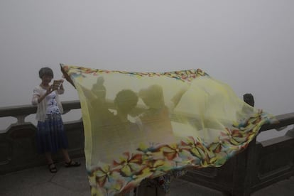 Turistas toman fotos de la niebla espesa que cubre las vistas desde un mirador en Hong Kong (China).