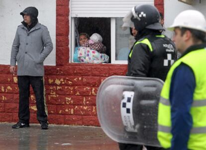 Una mujer del poblado observa desde la ventana de su vivienda la llegada de la policía y los obreros encargados del derribo de las infraviviendas de sus vecinos.