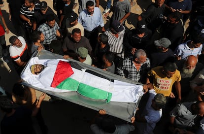 Dolientes cargan un cuerpo durante el funeral de palestinos que murieron por fuego israelí mientras intentaban recibir ayuda el lunes, y de palestinos que murieron en ataques israelíes nocturnos, en el hospital Al-Shifa de la ciudad de Gaza, el martes.