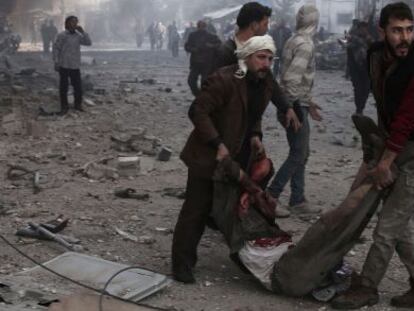 Dos sirios trasladan este viernes a una víctima de un bombardeo en las afueras de Damasco.