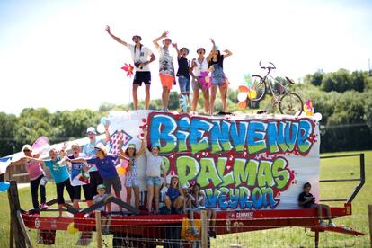 Un grupo de aficionados saluda desde un cartel que da la bienvenida a los ciclistas que compiten en el tour.