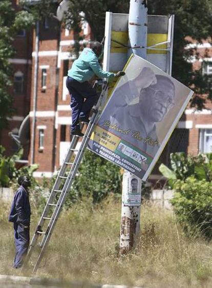 Empleados municipales retiran los carteles electorales de Mugabe de las calles de Harare el viernes.