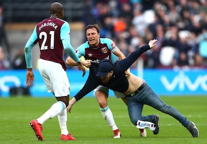 Mark Noble, del West Ham, agarra a un aficionado que había saltado al campo.