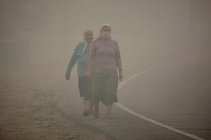 Dos mujeres caminan en una carretera de la región de Ryaza, a unos 180 kilómetros de Moscú. Al menos 293 incendios han sido extinguidos en las últimas 24 horas, aunque otros 500 permanecen activos a lo largo del país.