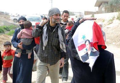 Una mujer lleva un pa?uelo con el retrato del presidente sirio, Bachar Asad, mientras abandona, junto a cientos de civiles, la zona de Guta Oriental, en la zona rural de Damasco (Siria), el 15 de marzo de 2018. 