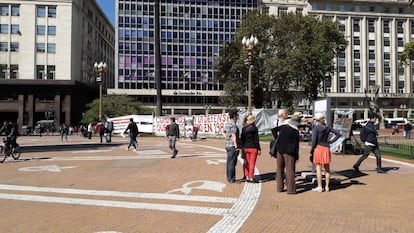 Turistas observan uno de los atriles colocados en la Plaza de Mayo, ahora junto a los pañuelos pintados de las Madres de Plaza de Mayo.