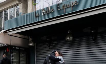 Dos personas se abrazan junto a la fachada del restaurante 'La Belle Equipe' durante el homenaje a las víctimas en el primer aniversario de los atentados de París.