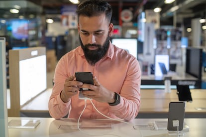 Un hombre revisa un telfono inteligente en una tienda. 