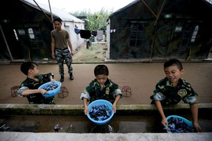 Tres niños que asisten al campamento militar lavan su ropa.