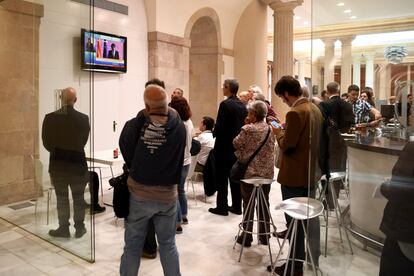 Varias personas se reúnen en el bar del Parlament de Cataluña para seguir en directo la comparecencia de Carles Puigdemont. 