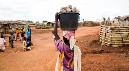 Una joven carga un cubo con pastillas de combustible en el campo de refugiados de Mbil&eacute; (Camer&uacute;n).