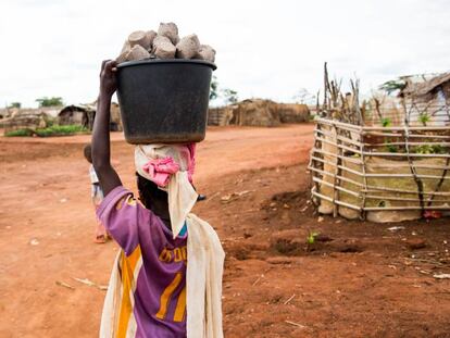 Una joven carga un cubo con pastillas de combustible en el campo de refugiados de Mbil&eacute; (Camer&uacute;n).