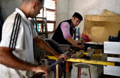 Cristian Baquina y Sergio Colazo retiran una tabla plástica del molde de metal en la fábrica de madera de la Fundación Müller.