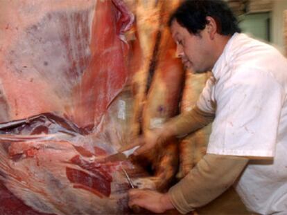 Un trabajador argentino corta carne vacuna en una cámara frigorífica.