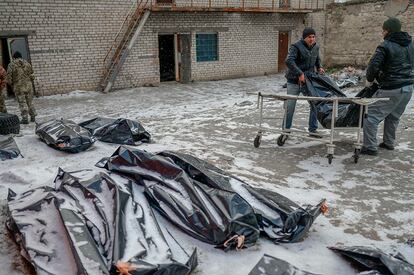 Dos hombres trasladan un cadáver de un patio nevado en Mykolaiv, este viernes. El papa Francisco realizó hoy un nuevo llamamiento para poner fin a la invasión rusa de Ucrania y a la guerra y denunció las duras repercusiones que tendrán que vivir los niños: "¡En nombre de Dios, deténganse!", exhortó.