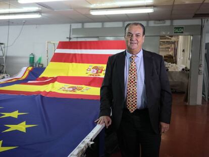 El empresario José Luis Sosa Dias, en su fábrica de banderas junto a insignias de España y de la Unión Europea.