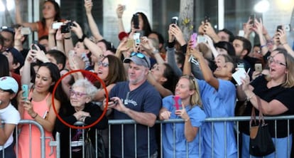 Idosa observa atores enquanto p&uacute;blico tenta fotograf&aacute;-los. 
 