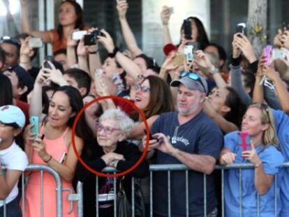 Idosa observa atores enquanto p&uacute;blico tenta fotograf&aacute;-los. 
 