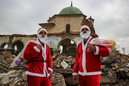 Los jóvenes Santa Claus posan para una foto delante de las ruinas de la Gran Mezquita de Al Nuri.