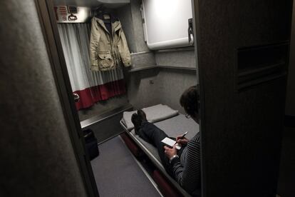 Uno de los pasajeros escribe en su cuaderno sentado en la litera y con la puerta del camarote abierta.
