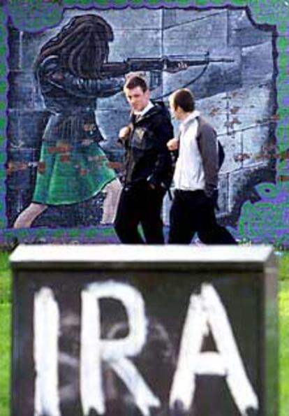 Dos jóvenes pasan junto a una pintada de apoyo al IRA en Belfast.