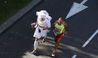 Una pareja de maratonianos, uno de ellos disfrazado de novia, por las calles de Madrid.