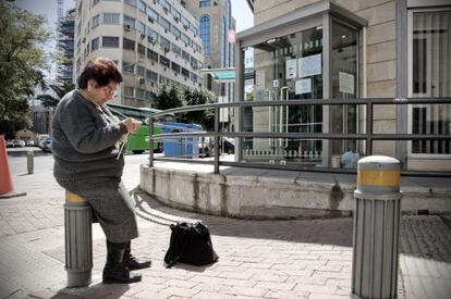 Una jubilada hace punto ante una sucursal del Banco de Chipre.