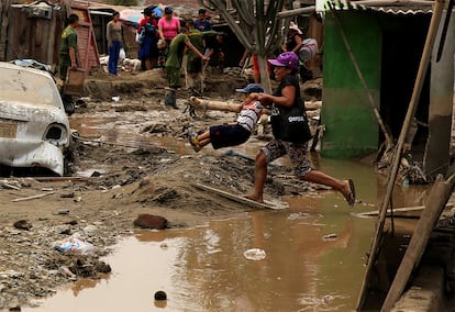 Una mujer ayuda a un niño a cruzar una calle inundada en Huachipa, en Lima (Perú), el 19 de marzo de 2017.