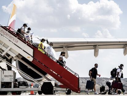 Viajeros descienden de la escalerilla de un avión de Iberia.