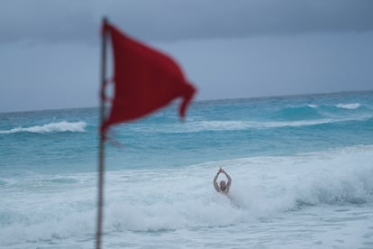 Un turista se baña en la playa de Cancún a pesar de la alerta roja señalada con una bandera, el 24 de septiembre de 2024.