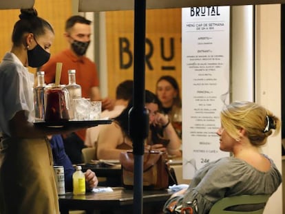 Una camarera sirve una bebida a un cliente en una terraza 