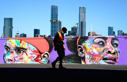 Un trabajador con mascarilla pasea ante un grafiti de Nadal y Serena.